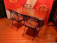 Full view of dining table with textured glass top and four matching black cast iron chairs.