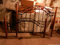 Wood and metal queen headboard and footboard with curved scrollwork designs and wooden posts with finial tops.