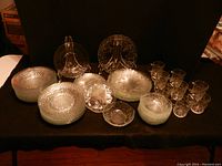 Clear glass dishes including basketweave pattern bowls and other bowls, plates, cups with intricate patterns. All clear glass with texture.