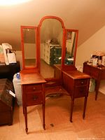 Front view of vintage wood vanity table with center seat and triple mirrors in folded position