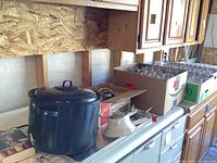 Photo showing a large black stock pot, a white funnel and a box of wide mouth canning jars.
