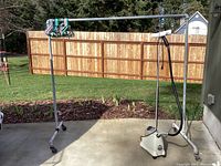 Full view of the heavy duty metal clothing rack on wheels with some hangers and the Jiffy steamer on the right side.