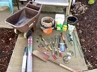 Full view of the garden tools, wheelbarrow, and other items on a beige mat outdoors