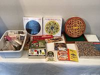 Wide view of vintage games, domino sets, card decks and jigsaw puzzles laid out on a table including carved black domino box and older card games