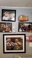 Wide shot of four framed photographs and two boxing gloves mounted on wall