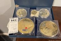 Set of six large collectible coins in plastic cases displayed inside a blue box. Featuring images of Donald Trump and Ben Franklin.
