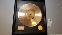 Front view of framed gold record replica featuring Elvis Presley with plaque and certification seal sticker.
