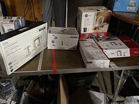 Group shot of all boxed items on table, including two faucets, shower trim kit, and hot water dispenser