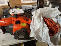 Husqvarna 125BV gas leaf blower with orange extension cord in plastic bag viewed from side
