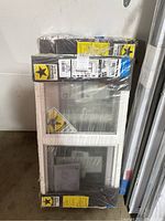 Two shrink-wrapped Pella Thermastar replacement sliding windows leaning against wall