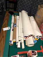 Rolled movie posters on a pool table showing numerous poster tubes and rolled sheets, some with shipping labels.