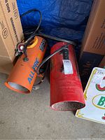 Both propane heaters side by side on the floor, showing overall condition and size.