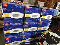 Nine stacked boxes of Globe brand 4-inch LED recessed lighting kits in a garage setting.