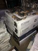 Four stacked boxes of Elida natural stone pebble tiles with pebbles visible on top.