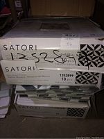 Boxes of Satori marble mosaic tiles stacked. Label indicates 10 pieces per box, 9.58 sq ft coverage.