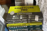 Stack of six boxes of Smartcore Pro Extreme Performance Waterproof Flooring visible with yellow and black packaging featuring Coretec technology logos.
