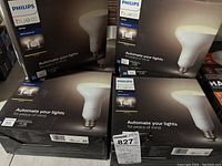 Six sealed boxes of Philips Hue White BR30 Starter Kits stacked, showing front labeling and brand.