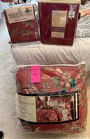 Photo showing packaged red floral bedding items including comforter set, valance, and bedding covers.