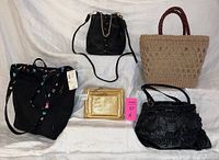 Overview photo showing all five purses displayed flat on white background: beige wicker tote, black handbag with gold chain, black Nordstrom tote with colorful lining, small black zippered purse with gold chain, and gold zipper pouch