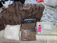 Photo of multiple bedding sets boxed and packaged including Ralph Lauren Hillcrest Spa collection sheets and duvet cover, Isaac Mizrahi white sheet set, and a brown bird patterned sheet.