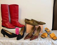 Five pairs of women's shoes size 9 shown together on table including red knee-high boots, black heels, green quilted wedges, patterned red and brown heels, and yellow slide sandals.