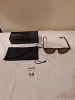 DIFF sunglasses with box and pouch on white surface under indoor lighting