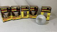 Five Satco Reflector Flood Indoor Lights in original boxes, displayed side by side with one bulb removed for view.
