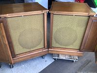 Front view of both speaker cabinets with fabric grilles exposed, doors open
