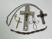 Overview of religious collection including several crosses and a bracelet, displayed on white background.