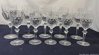 Front view of ten Waterford crystal wine glasses arranged in two rows on a dark blue cloth background, showing cut glass designs clearly.