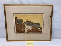 Framed colored engraving showing old village houses and church in winter scene with snow patches