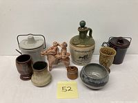 Photo showing one Tallamore Dew Irish whiskey ceramic bottle with stopper, alongside miniature pottery vases, two ceramic containers with lids, small brown miniature container, and a ceramic figurine of two children on a donkey.