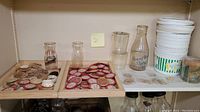 Shelf display of various vintage milk bottle caps, glass milk bottles, and plastic ice cream containers