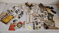 Overview of the lot showing a large quantity of vintage 1940s black and white photographs, film negatives, cards, letters, and other ephemera spread on a surface.