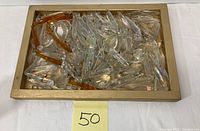 Top-down image showing a collection of clear, iridescent, and amber hanging glass prisms inside a wooden tray.