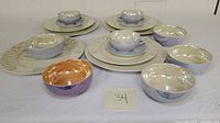 Partial service set arranged on table showing bowls, plates, cups, and saucers with reflective luster glaze.
