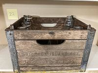Wooden vintage Aquidneck Island Dairy crate showing side with logo, metal reinforcements and handle