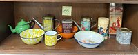 Full view of enamelware and vintage tins on shelf showing all items included in lot