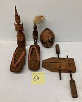 Overview of full lot including carved wood ethnic figures, egg-shaped container, wooden shoes, and vintage carpenter clamp