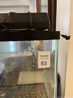 Front view of the glass aquarium tank with filter hood and power cord.