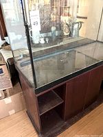View of the aquarium tank sitting on wooden stand with open shelves and double doors.