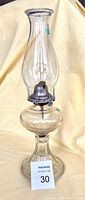 Full side view of the pressed glass oil lamp showing chimney, metal burner, reservoir, and base with patterned detail.