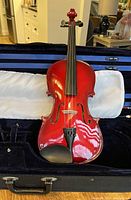 full view of red violin seated in case