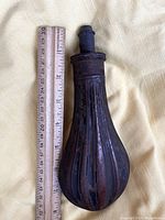 Top view of Civil War era gunpowder flask showing fluted design and stopper, placed next to ruler showing size approximately 6 inches.