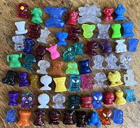 Multiple colorful Crazy Bones collectible plastic figurines arranged on a wooden surface showing a variety of character shapes and colors.