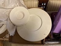 Overhead image of the two ceramic slumping molds placed on a surface with white tissue and a box underneath.