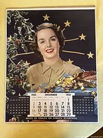 December 1951 calendar page with a portrait of a woman in a beige blouse, holly in the background, with clear calendar layout.