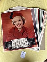 Stack of large 1952 calendar pages showing January page with woman in red coat and hat.
