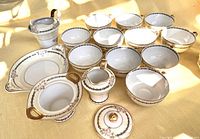 Tea set components laid out showing cups, saucers, cream and milk pitchers, sugar bowl with lid, and biscuit dish with protective covers.