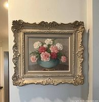 Full front view of the framed oil painting of carnations in blue bowl featuring the signature and decorative plaster frame.